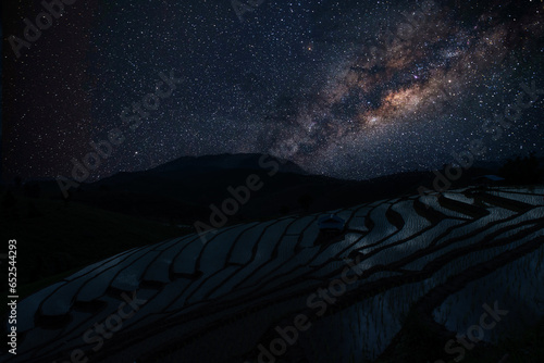 Milky way in the dark night over Pa Bong Piang rice terrace fields and light from countryside village hill of Chiang Mai Thailand. © nopporn