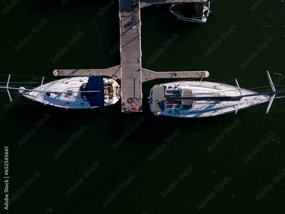 Aerial view of a yacht marina by the sea, adorned with elegant yachts, creating a picturesque maritime scene.