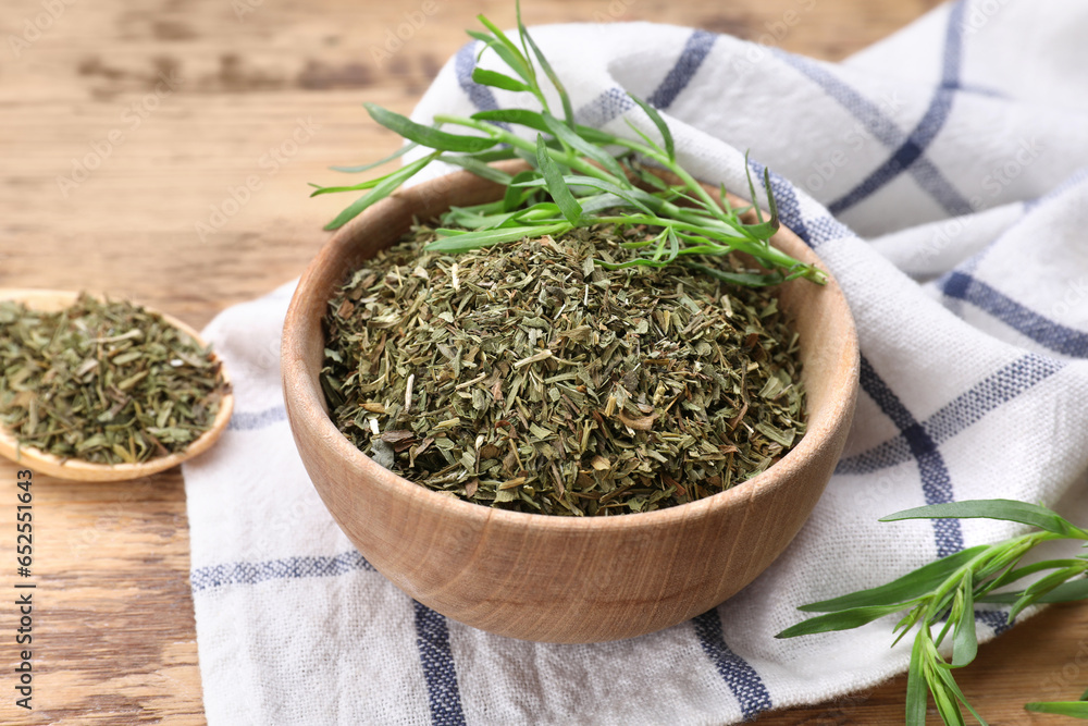 Dry and fresh tarragon in bowl on wooden table, closeup Dry and fresh tarragon in bowl on wooden table, closeup