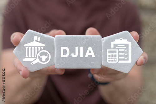 Trader or financier holding white foam blocks with icons and abbreviation: DJIA. Concept of DJIA Dow Jones Industrial Average. photo