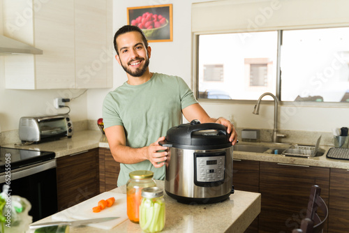 Happy young man cooking lunch food with a pressure cooker in the kitchen