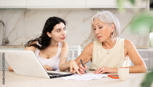 Elderly woman while discussing deal with saleswoman in kitchen