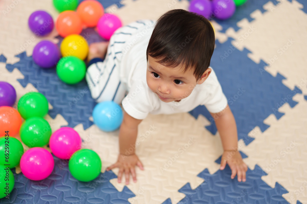 Obraz premium infant baby playing colorful balls in playpen