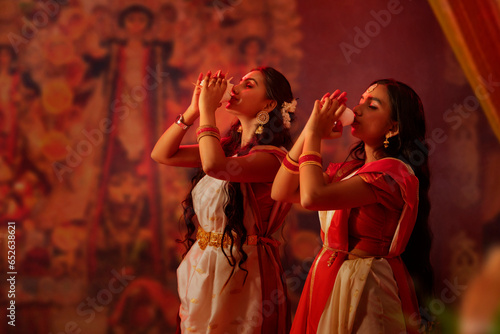 Two Bengali sister playing conch on the occasion of Durga Puja