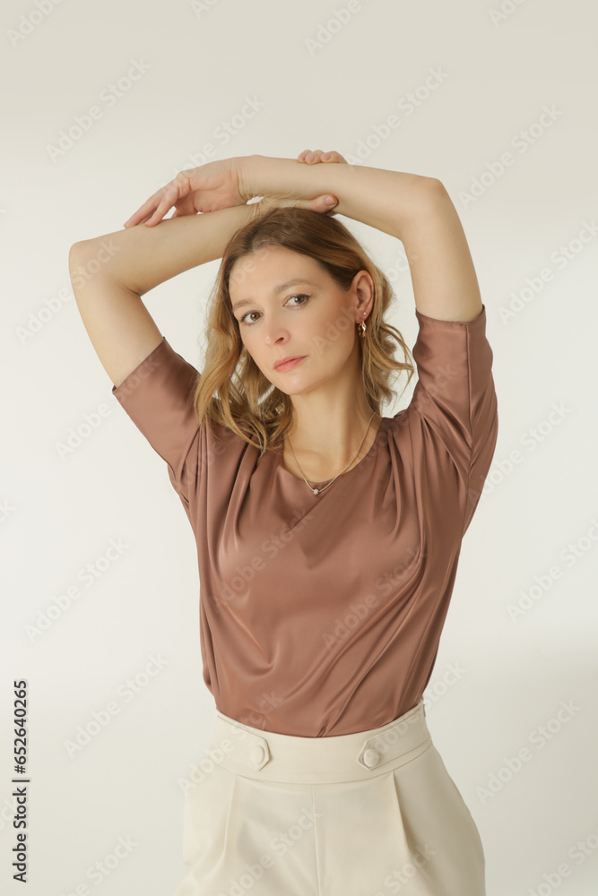 Serie of studio photos of young female model wearing simple beautiful outfit, silk satin blouse and white wide leg trousers Serie of studio photos of young female model wearing simple beautiful outfit, silk satin blouse and white wide leg trousers