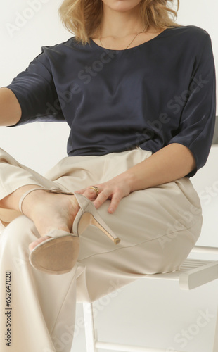 Serie of studio photos of young female model wearing simple beautiful outfit, silk satin blouse and white wide leg trousers 