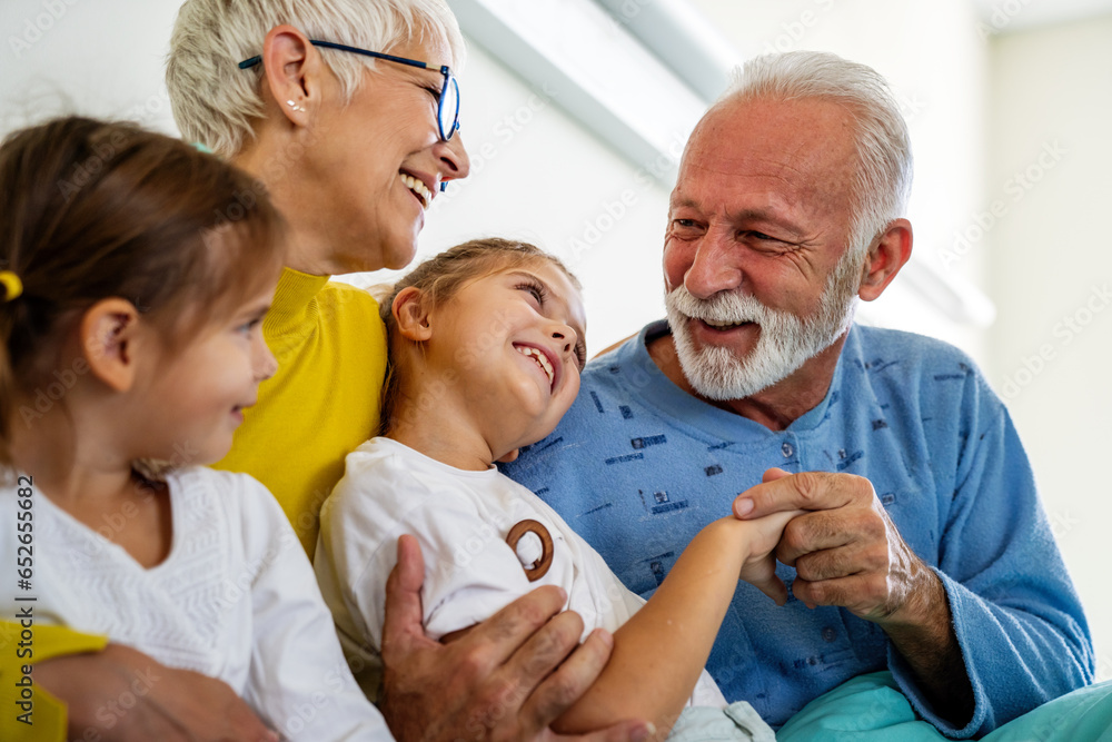 Fototapeta premium Happy grandchildren visiting grandfather at hospital ward. Support, family and healthcare concept.