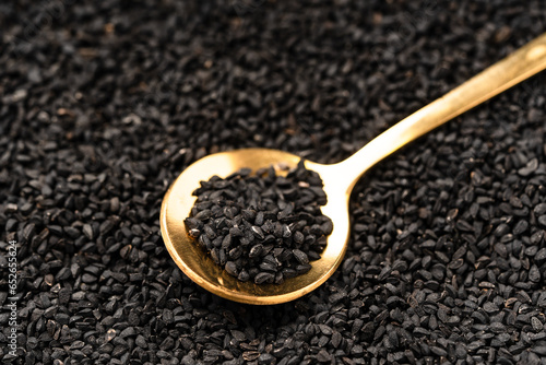 Black cumin seeds on golden spoon macro photography