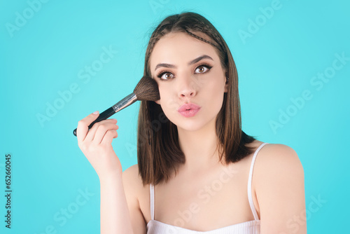 Young woman applies powder on the face using makeup brush. Beautiful girl doing contouring apply blush on cheeks. Face beauty cosmetics. Fresh skin and natural make up. Powder blush on facial skin.