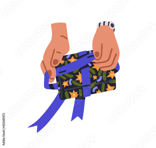 Hands packing holiday gift box, tying ribbon bow. Preparing festive package, ...