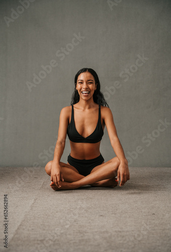 Smiling Multiethnic female sitting crossed legged getting ready for yoga work out
