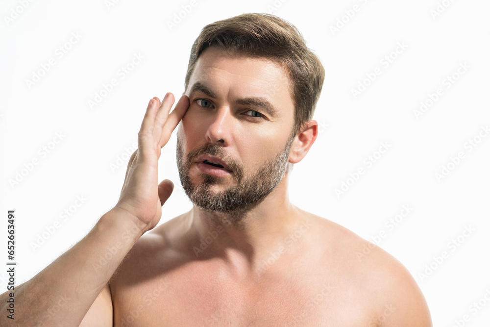 Fototapeta premium Beauty portrait of handsome man with moisturizing cream on face, isolated background. Skincare routine concept. Male haircut, mustache and beard. Male beauty. Shaving, hair styling.