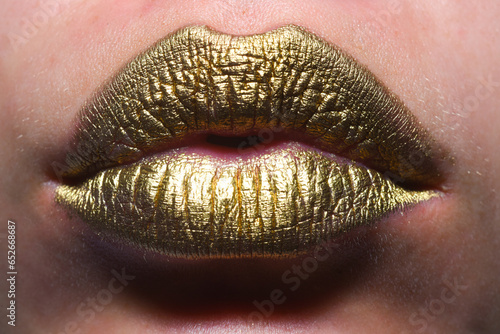 Gold lips. Gold paint on mouth. Golden lips. Luxury gold lips make-up. Golden lips with creative metallic lipstick. Gold metal lip. Sensual woman mouth, clse up, macro.