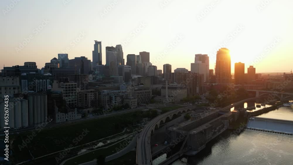 Aerial View of Downtown District of Minneapolis, Minnesota at Sunset Golden Hour with the Sun Hidden Behind a Tall Building. Aerial Diagonal Landing Aerial View of Downtown District of Minneapolis, Minnesota at Sunset Golden Hour with the Sun Hidden Behind a Tall Building. Aerial Diagonal Landing