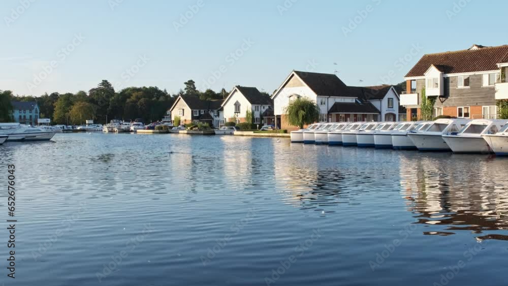 . Low down view of rental properties and hire boats on the River Bure in Wroxham in the heart of the Norfolk Broads. Captured early morning at sunrise . Low down view of rental properties and hire boats on the River Bure in Wroxham in the heart of the Norfolk Broads. Captured early morning at sunrise