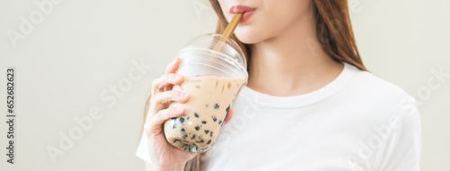 Beverage and food concept, Happy asian young woman hand holding plastic cup, glass of drink bubble, pearl milk tea with straw, cute girl drinking ice cold tea with tapioca boba ball popular in Taiwan.
