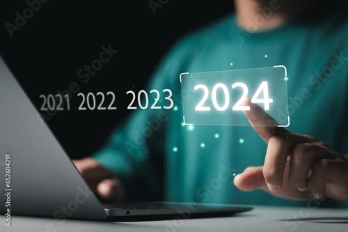 Market trend for 2024. Businessman touching virtual number 2024 for Merry christmas and happy new year concept. End of the old year and start of new business in 2024.