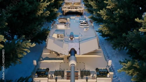 An aerial view over an armored military tank platoon taking cover under the spruce trees of a snow-covered road.
