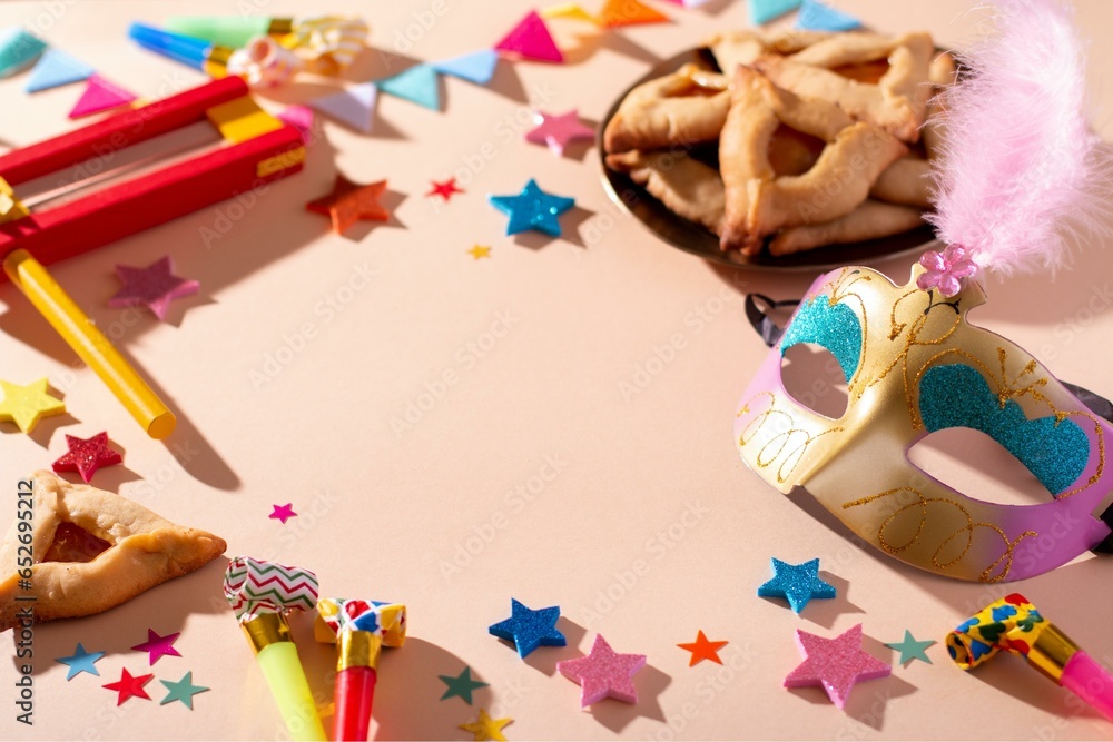 Fototapeta premium Purim frame with hamantaschen cookies, carnival mask, holiday decor in hard light
