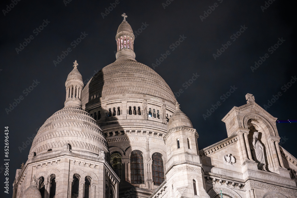 Obraz premium The Basilica of Sacre Coeur de Montmartre illuminated in the evening. Roman Catholic church and minor basilica in Paris dedicated to the Sacred Heart of Jesus. France