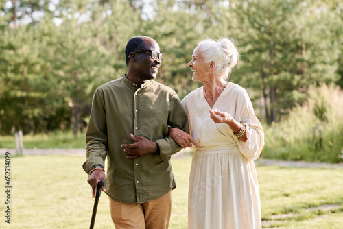 Happy senior couple enjoying their walk in the park, they talking to each other and laughing photo