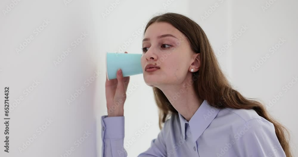 Curious student intern woman puts glass to wall in office while covering mouth with hand. Surprised female employee overhears an argument between colleagues or neighbors Curious student intern woman puts glass to wall in office while covering mouth with hand. Surprised female employee overhears an argument between colleagues or neighbors