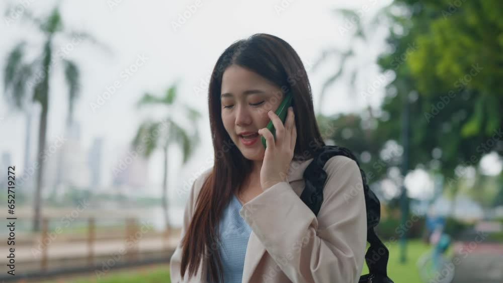 Beautiful young Asian woman talking on smartphone while walking at outdoors. Happy Asian women talking through smartphone. Lifestyle concept Beautiful young Asian woman talking on smartphone while walking at outdoors. Happy Asian women talking through smartphone. Lifestyle concept
