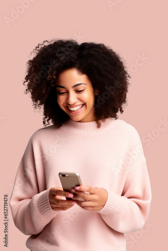 woman of color with curly hair looking at her smartphone with rose pink background
