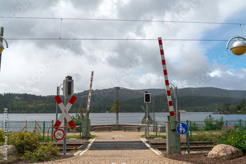 Railroad crossing on the coastline of the lake named "Schluchsee", close to Freiburg, Baden-Wurttemberg, Germany. Sky with clouds on the background.