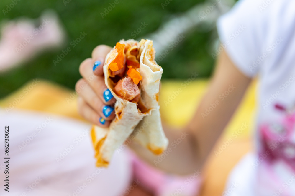 Close up of hands handling food outdoor. Child girl hand holding deletions pita. Street food concept