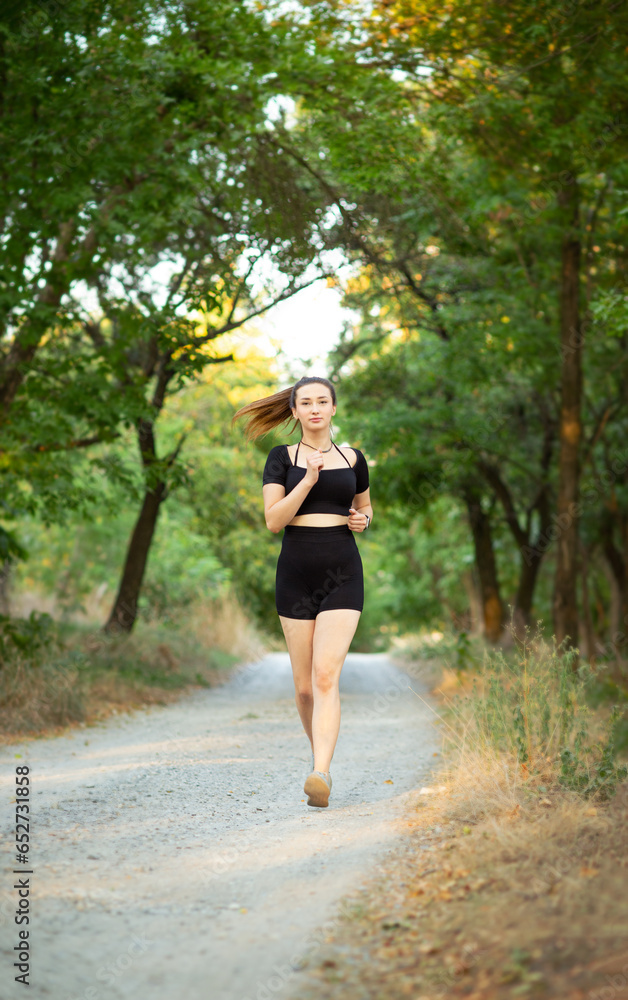 young woman running in forest park. Girl jogging at sunset on nature, health and sport concept