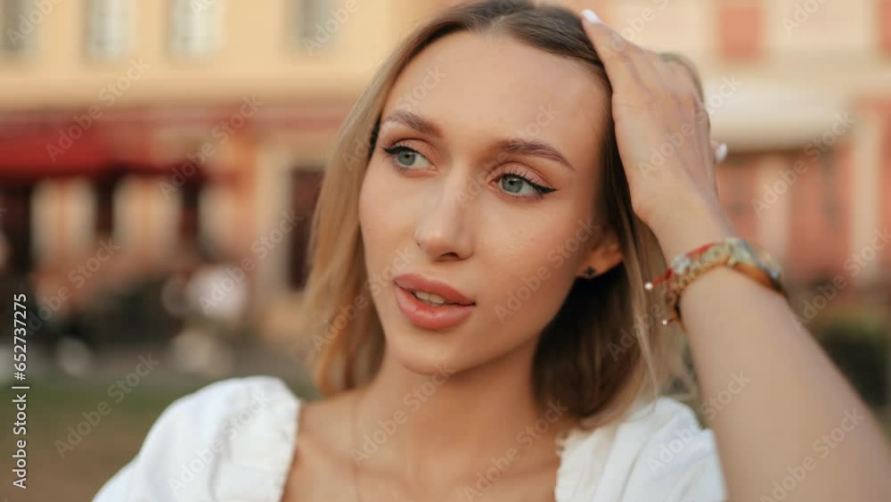 Close up face of attractive young woman blonde sexy smiling with long hair. Portrait of a gorgeous girl looking at the camera and smiling warmly outdoors