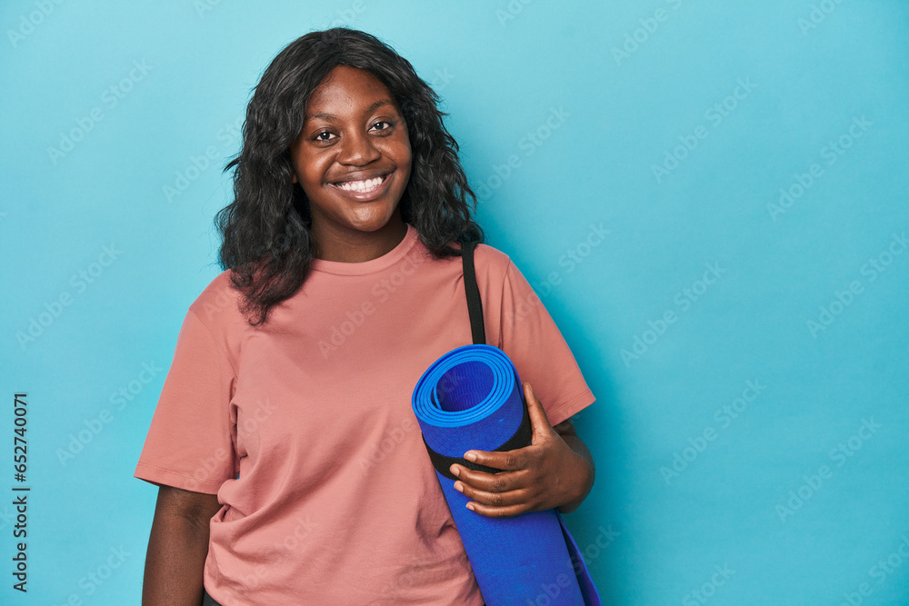 Curvy woman ready to practice yoga on a blue backdrop Curvy woman ready to practice yoga on a blue backdrop
