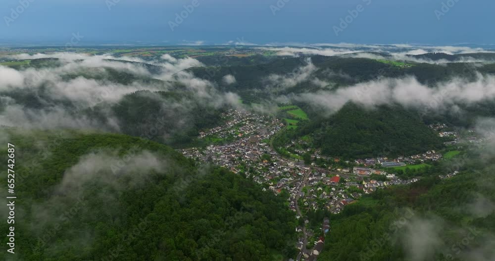 Drone flight over clouds and green fresh forest in hilly Europe, Germany. Aerial view around the foggy forest Germany. On a cloudy day in spring. Quiet German village located in a forest area Drone flight over clouds and green fresh forest in hilly Europe, Germany. Aerial view around the foggy forest Germany. On a cloudy day in spring. Quiet German village located in a forest area