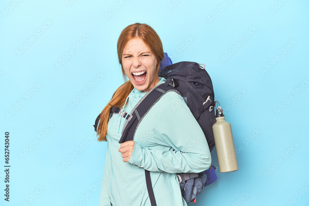 Redhead traveler with backpack and mat in studio screaming very angry and aggressive. Redhead traveler with backpack and mat in studio screaming very angry and aggressive.