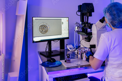 Female scientist embryologist, assisted reproductive technologies, using microscope fertilization vet examining sample through microscope in embryology laboratory. Healthcare and medical concept photo