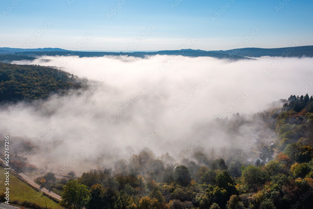 Bird's-eye view of the forests near Presberg/Germany in autumn and morning fog over the Wisper Valley in the background