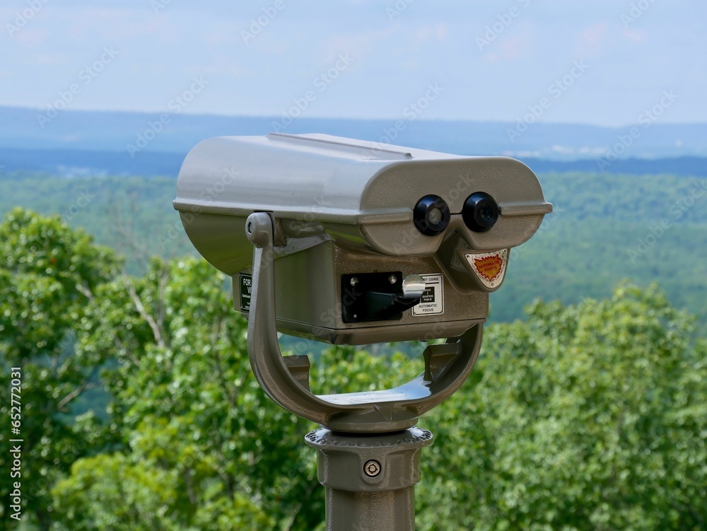 Binoculars situated atop a grassy hill, with mountain peaks visible in the background Binoculars situated atop a grassy hill, with mountain peaks visible in the background