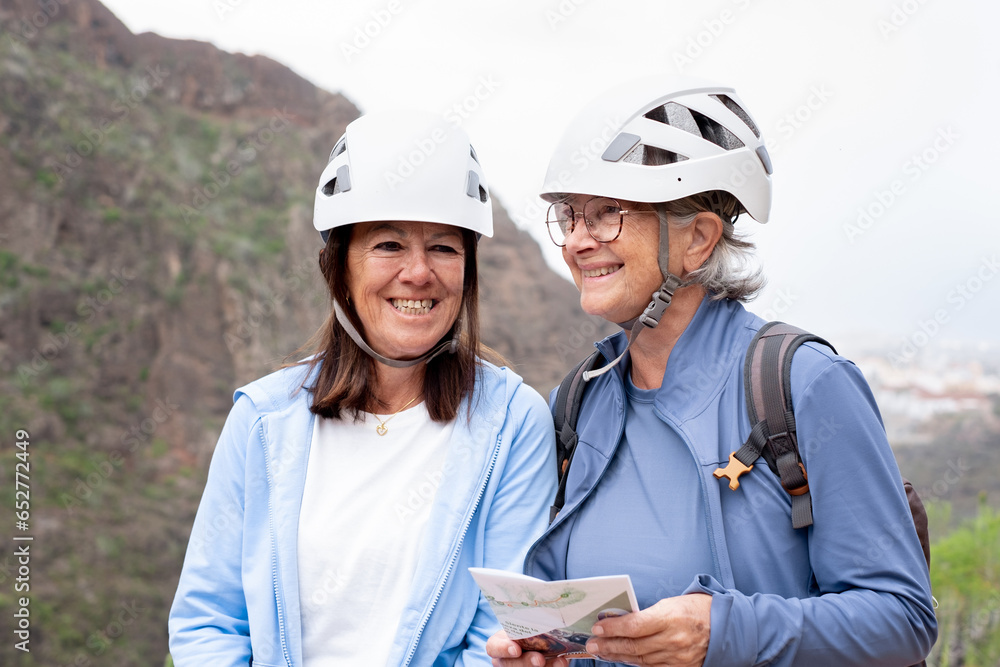 Senior women hikers with protective helmets standing on the top of mountain in a trekking day - Smiling female tourists enjoying holidays and healthy lifestyle - Freedom sport concept Senior women hikers with protective helmets standing on the top of mountain in a trekking day - Smiling female tourists enjoying holidays and healthy lifestyle - Freedom sport concept