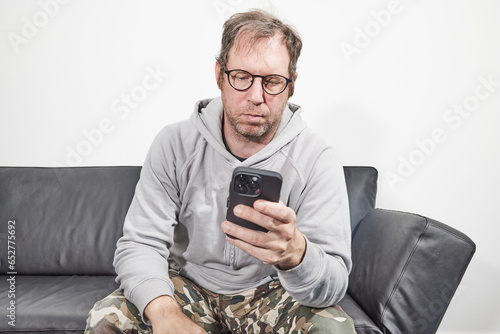 Man with glasses at home using mobile smart phone