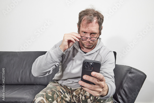 Man with glasses at home using mobile smart phone