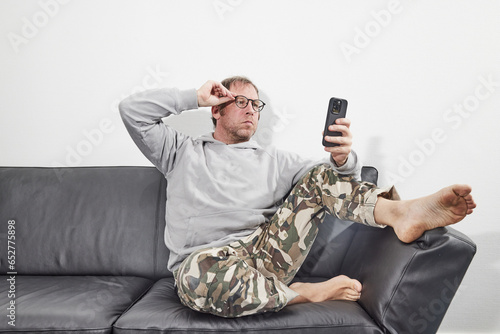 Man with glasses at home using mobile smart phone