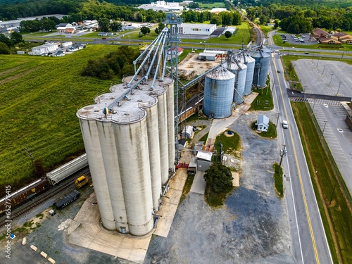 Obraz na plátně Aerial view of a cargo train by a farm with tall grain elevators and tanks in De