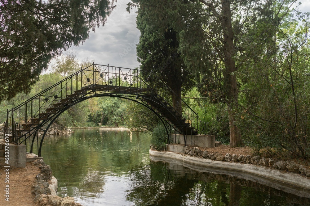 Metal bridge crossing a river on a cloudy day in one of the most important parks in Madrid.