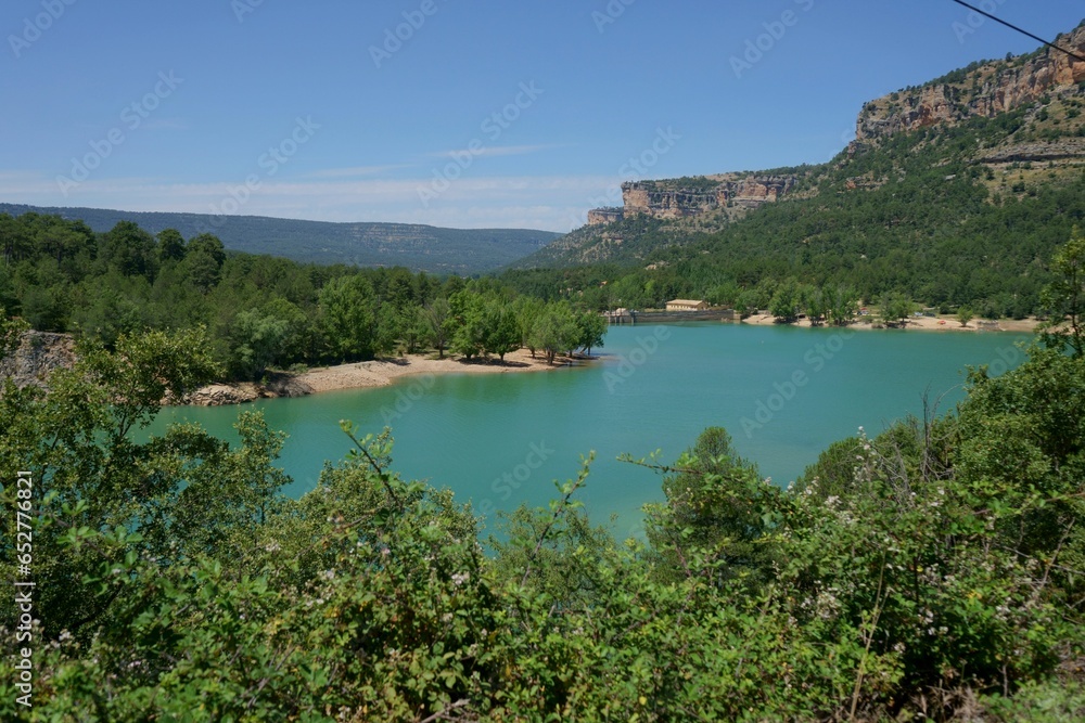 Green and blue landscape. Turquoise water lake and green vegetation and trees on a summer day.