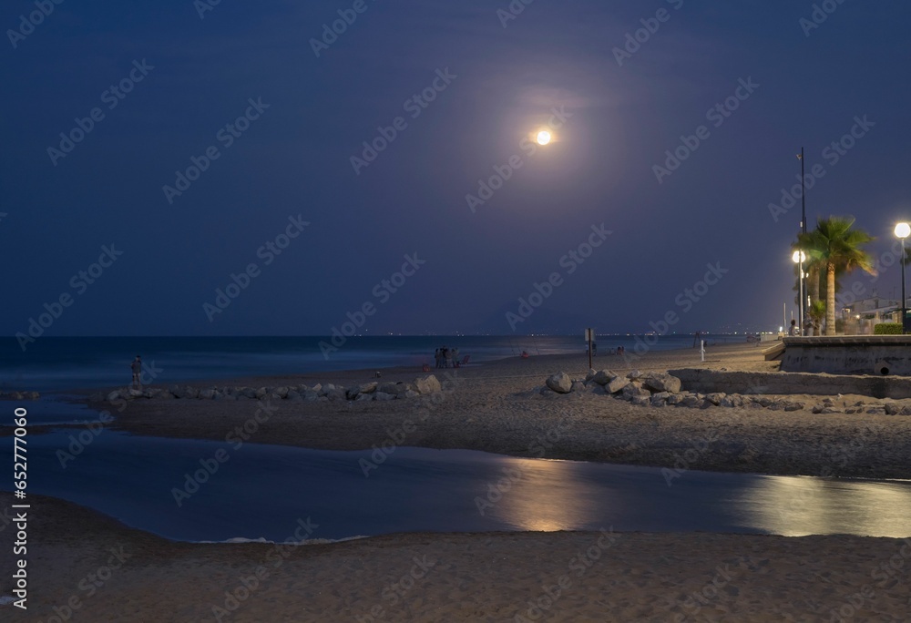 Sunset with the moon in the background reflected in the sea on the beach of Gandia, Valencia. Spain.