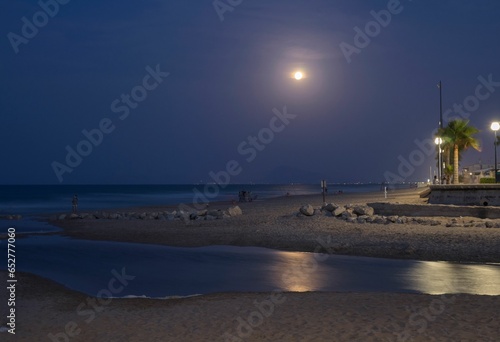 Sunset with the moon in the background reflected in the sea on the beach of Gandia, Valencia. Spain.