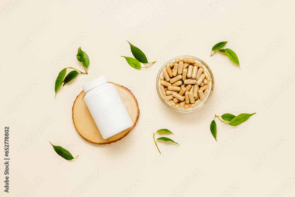 Vitamin medical bottle mockup on wooden podium with pills in jar, green leaves, organic medication. Natural herbal supplement, top view - obrazy, fototapety, plakaty 