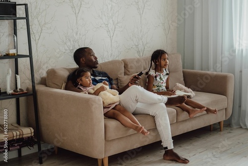 Hispanic father with his doughters on sofa photo