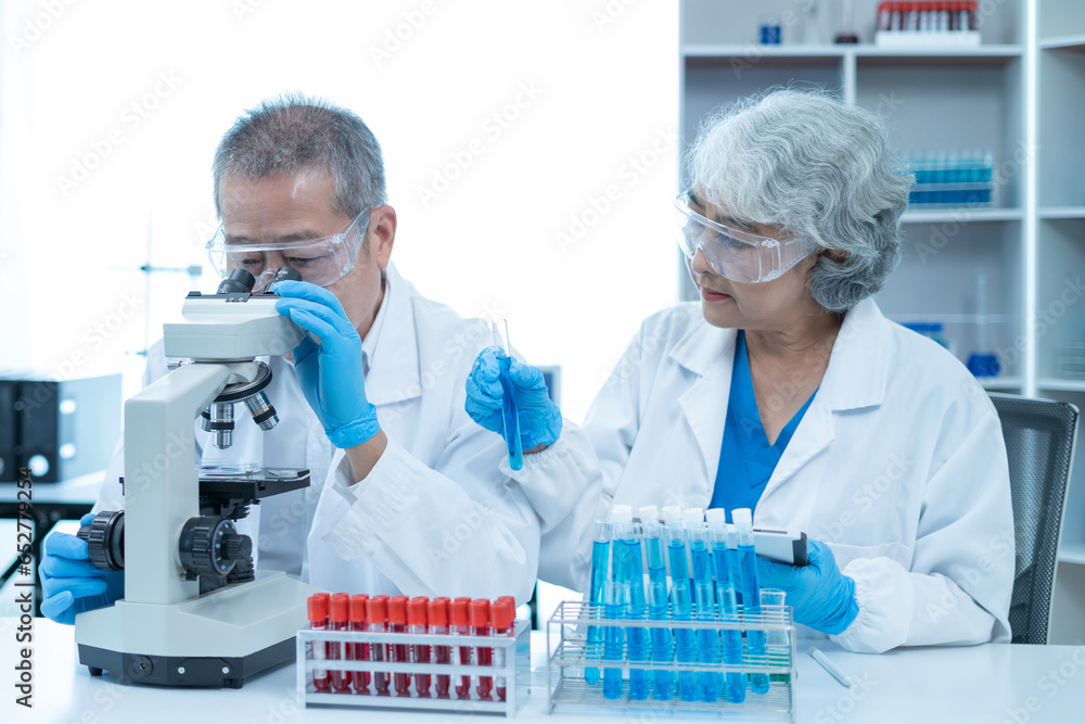 Team of biochemical research scientists working with a microscope for vaccine development in pharmaceutical research labeling. Team of biochemical research scientists working with a microscope for vaccine development in pharmaceutical research labeling.
